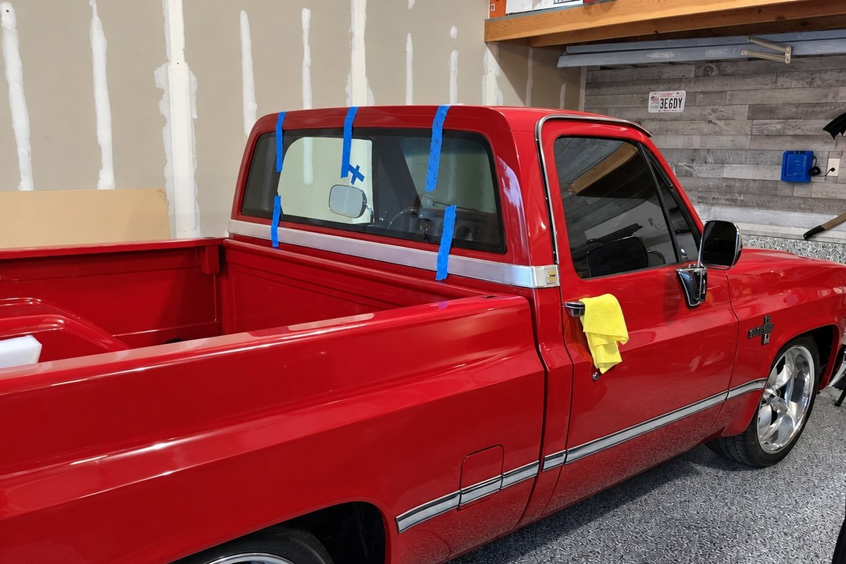 Red classic Chevrolet pickup with its newly fitted rear cab window held by blue tape