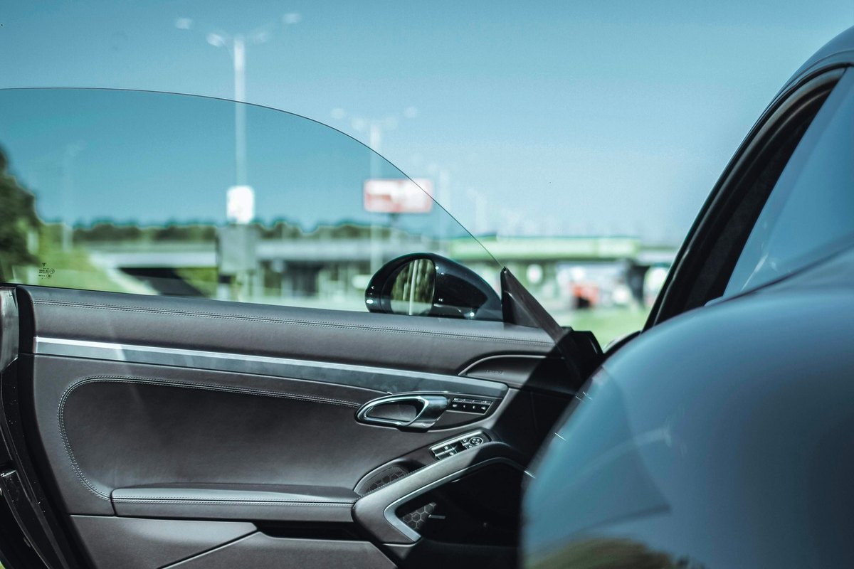 Open black sports car door with its frameless window glass raised above the leather trim