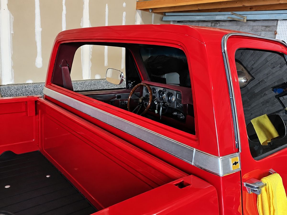 Red classic Chevrolet pickup with its cab back window out, seen from the bed